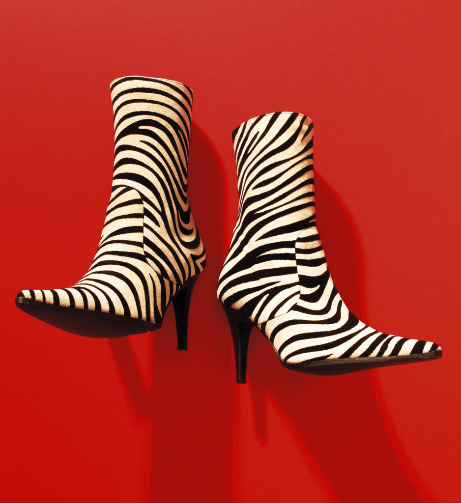 Photograph of black and white zebra boots on red background